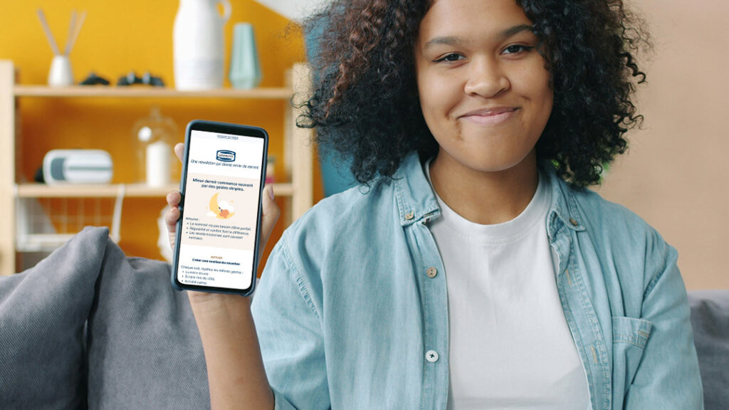Photo de la persona 1 heureuse tenant un smartphone avec la newsletter Simmons